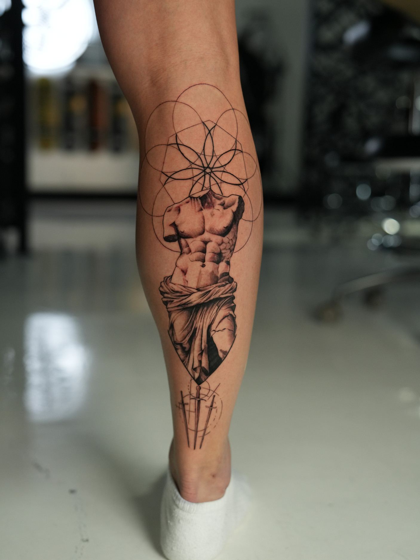 Greek statue torso with flower of life sacred geometry calf tattoo